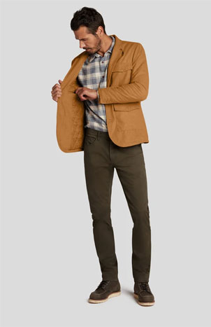 A male model with pant shirt and over coat wearing shoes checking his inner pocket of coat