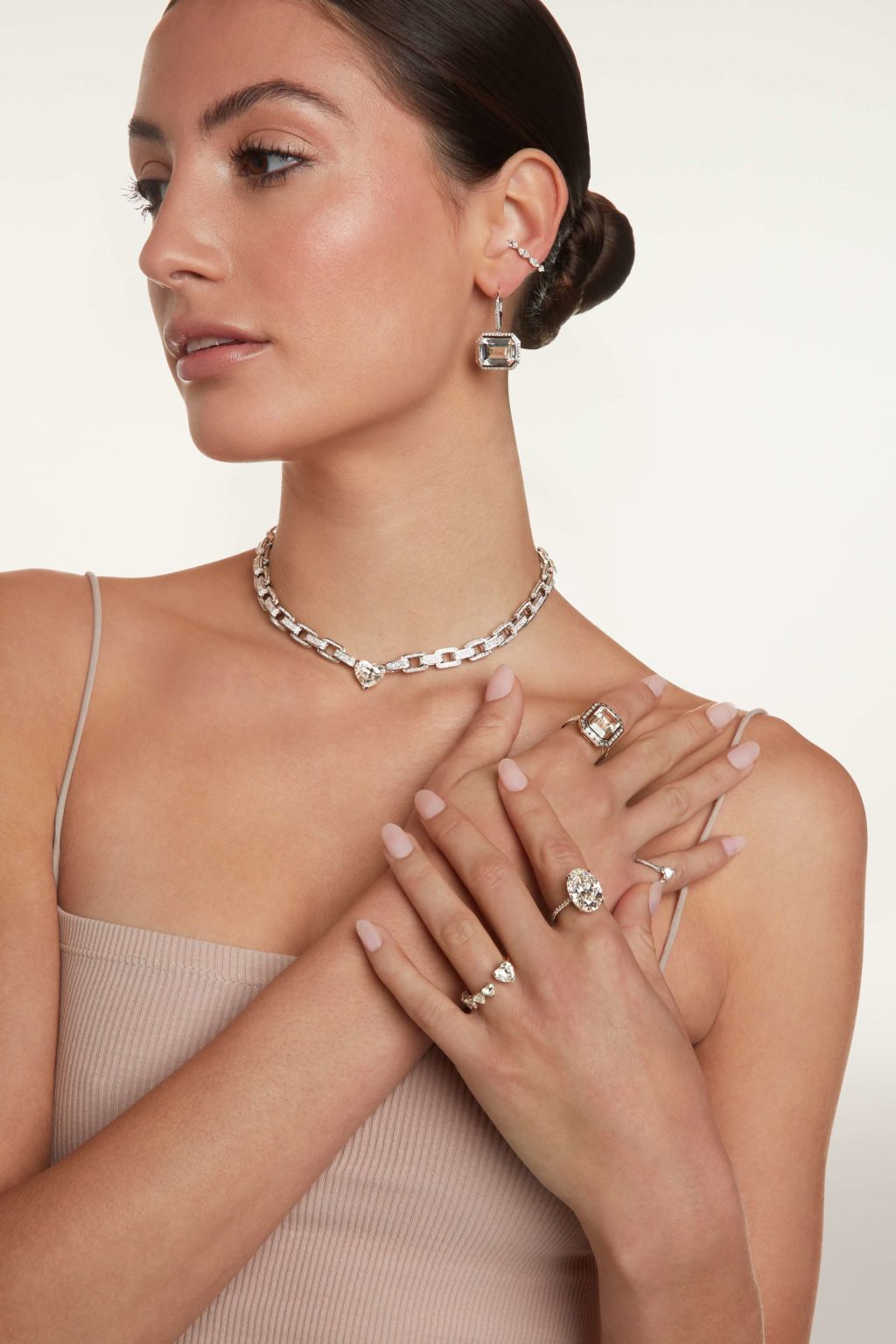 A female model touching her collar bone area showing her rings and necklace