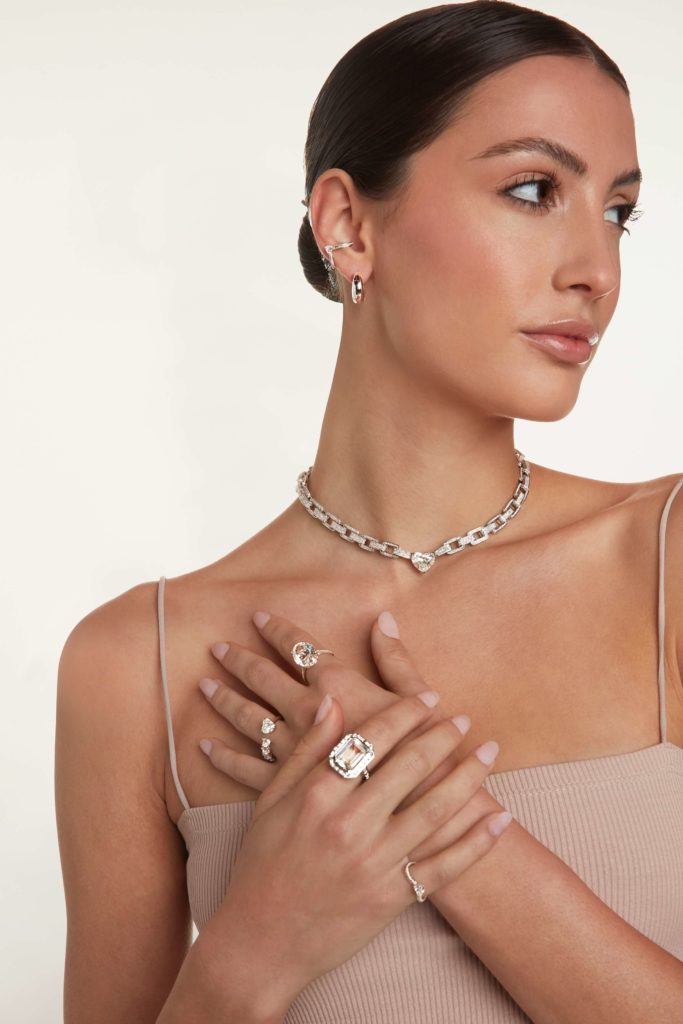 A female model touching her collar bone area showing her rings and necklace