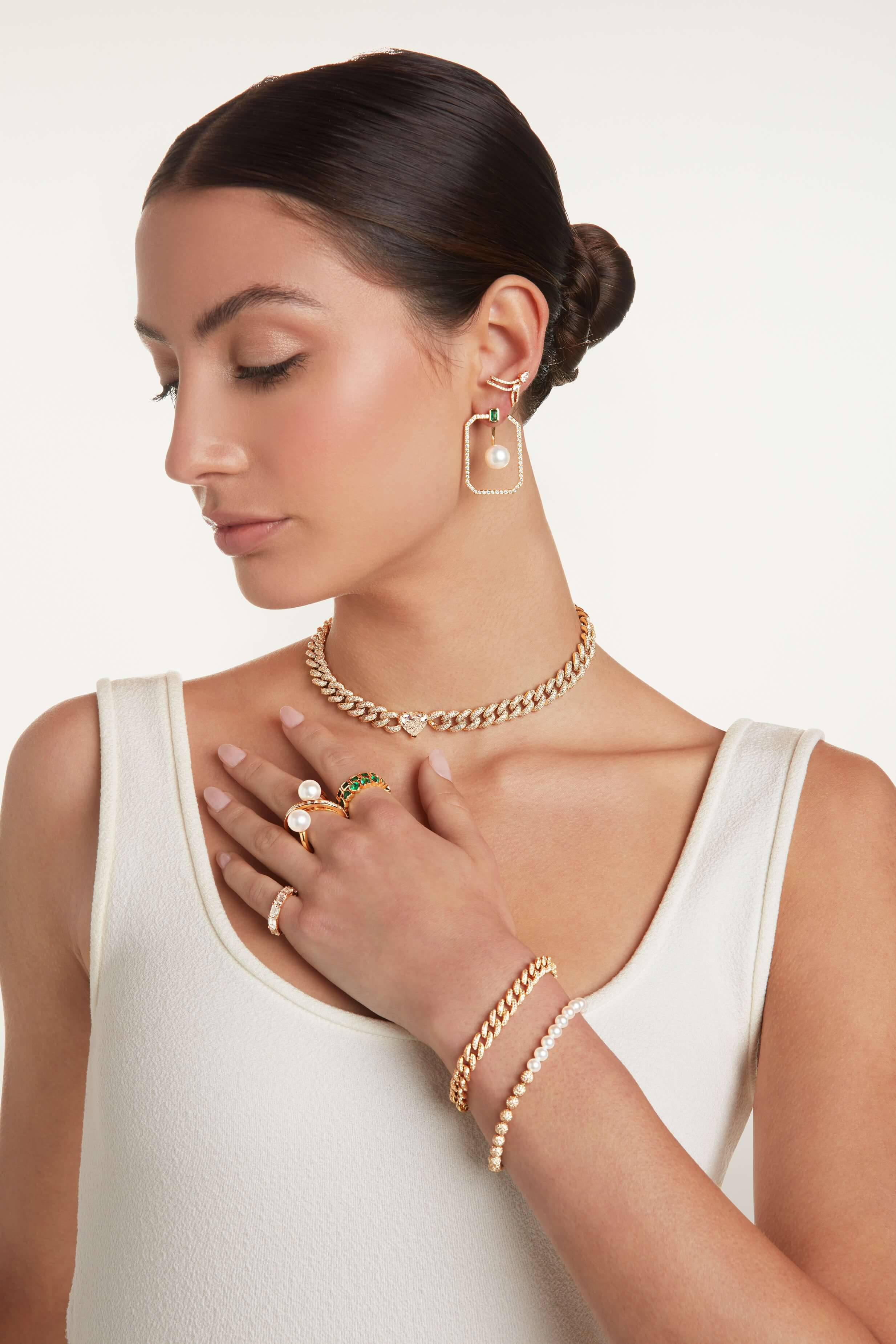 A female model touching her collar bone area showing her rings, bracelet and necklace