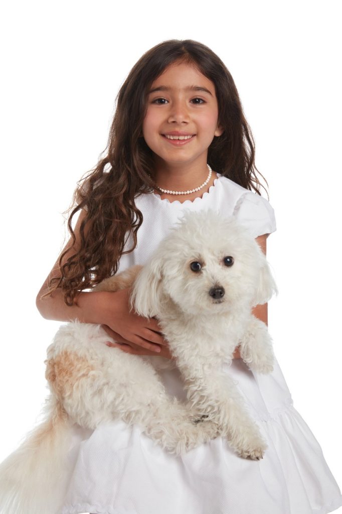 A smiling small girl with white dress and white puppy