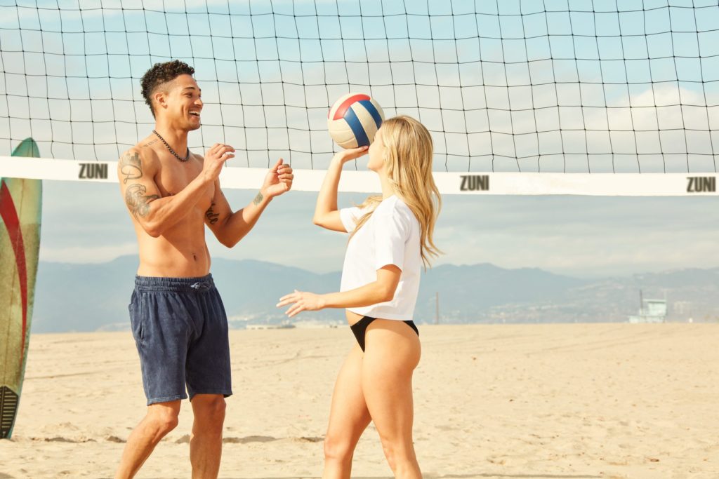 A smiling couple playing with beach volley ball