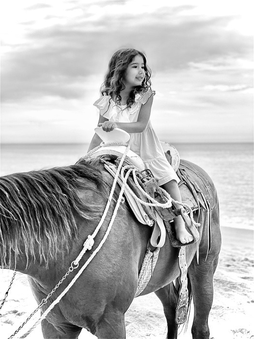 Black and white of a child sitting on an horse at beach