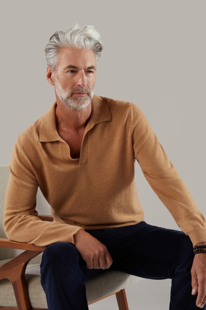 An older male model with trousers and long sleeve tshirt sitting on a chair