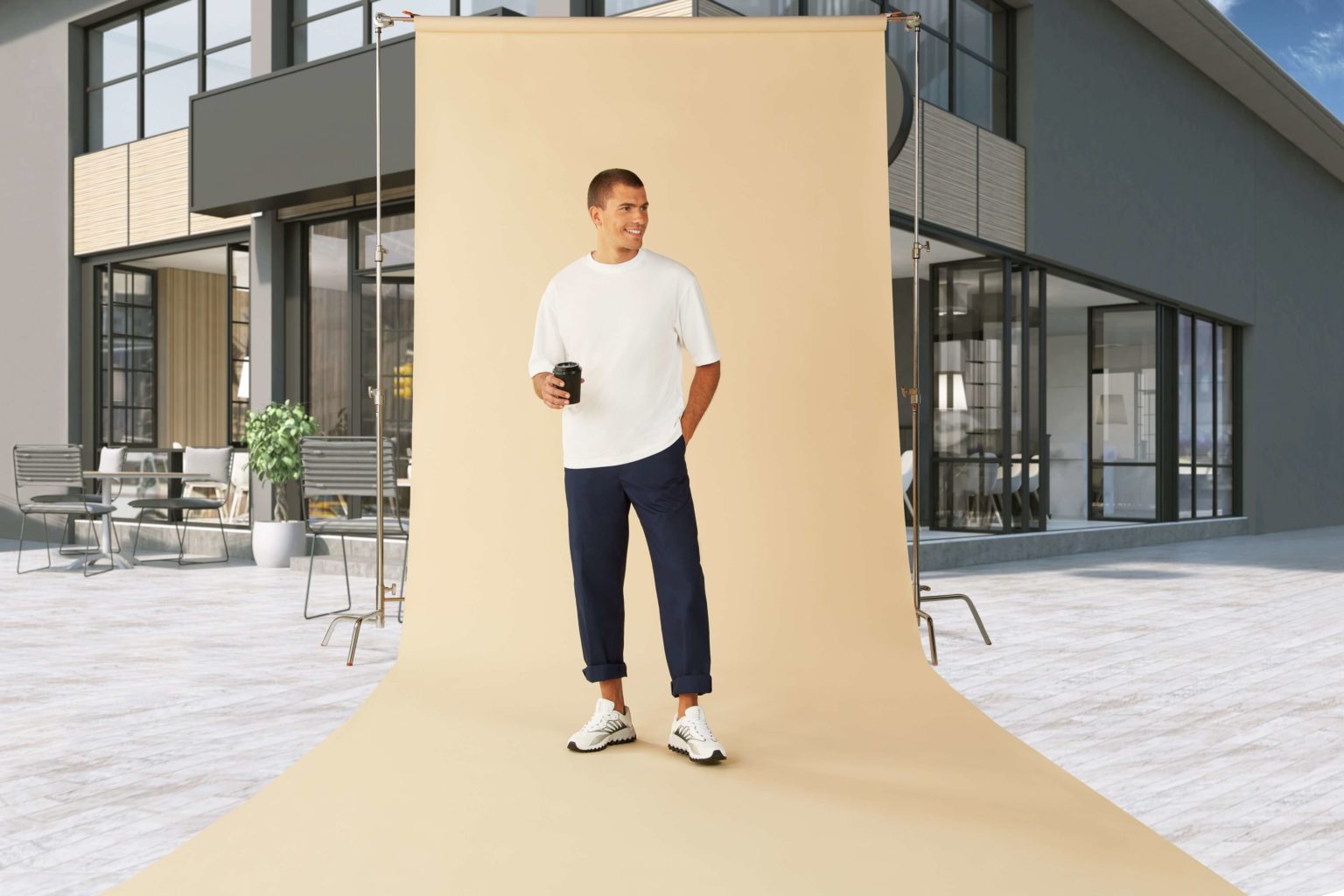 A male model in a leisure attire with a coffee holder and a building background setup for photography