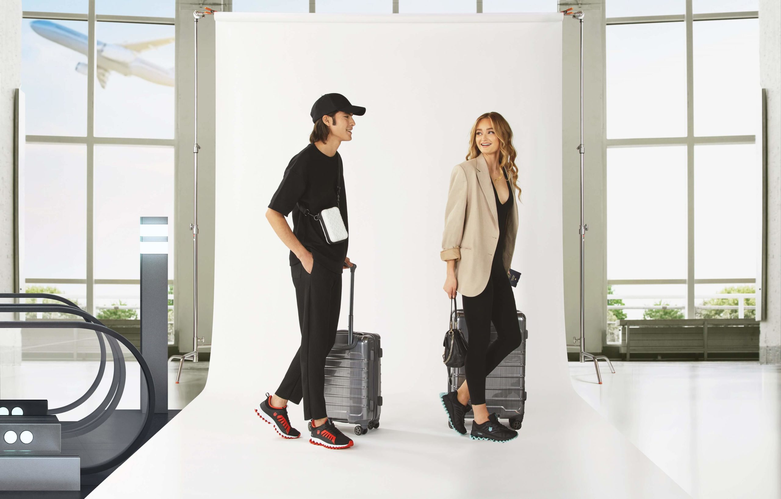 A male and female models in an airport backdrop carrying travel suitcases