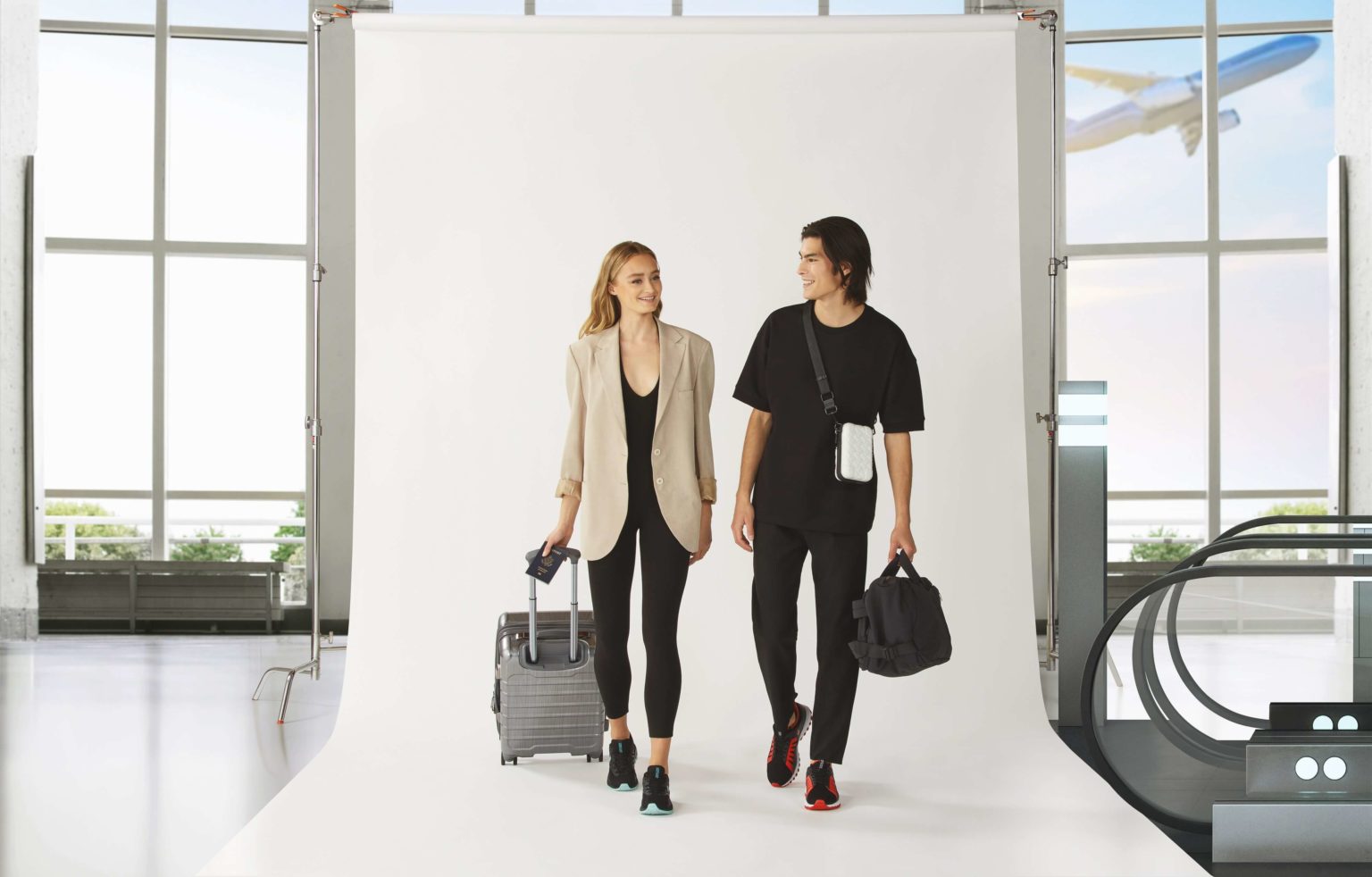 A male and female models in an airport backdrop carrying travel suitcase and a travel bag