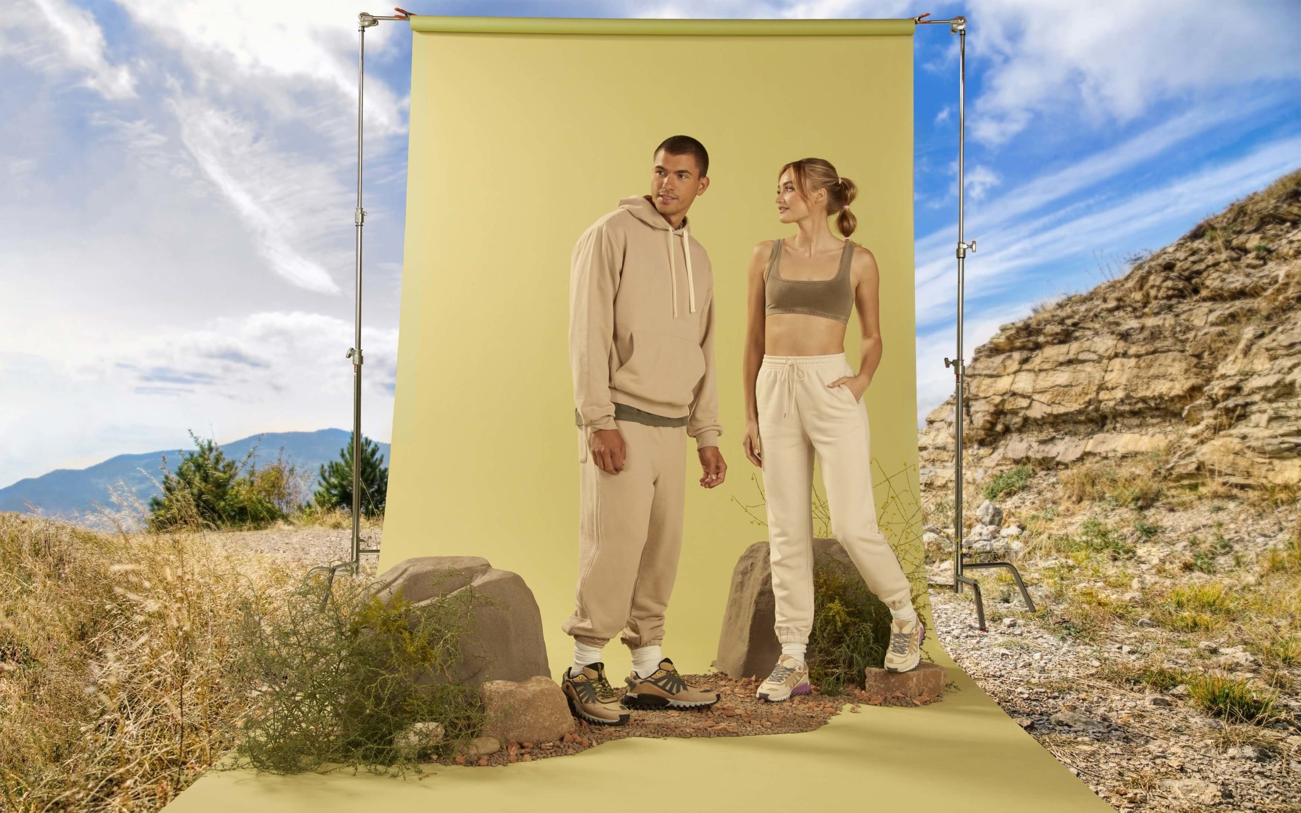 A male and female models in front of landscape setup for photography with all green shades in background