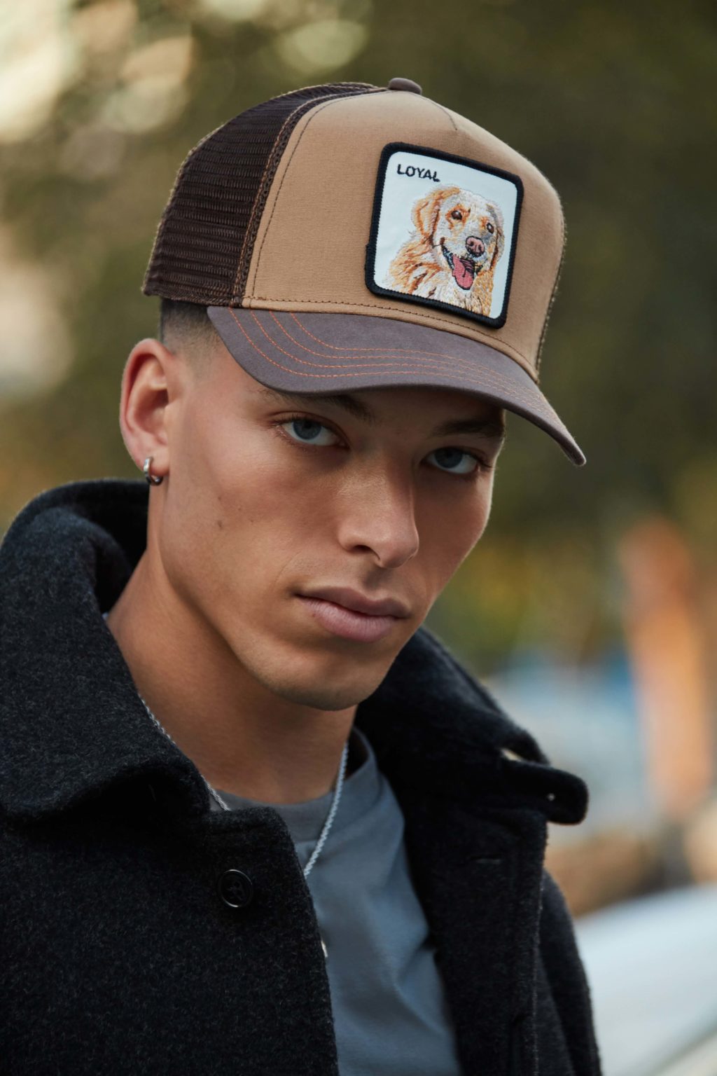 A male model with black sweater and a cap