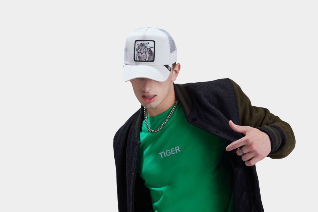 A young male model with green color tshirt and black sweater and a cap