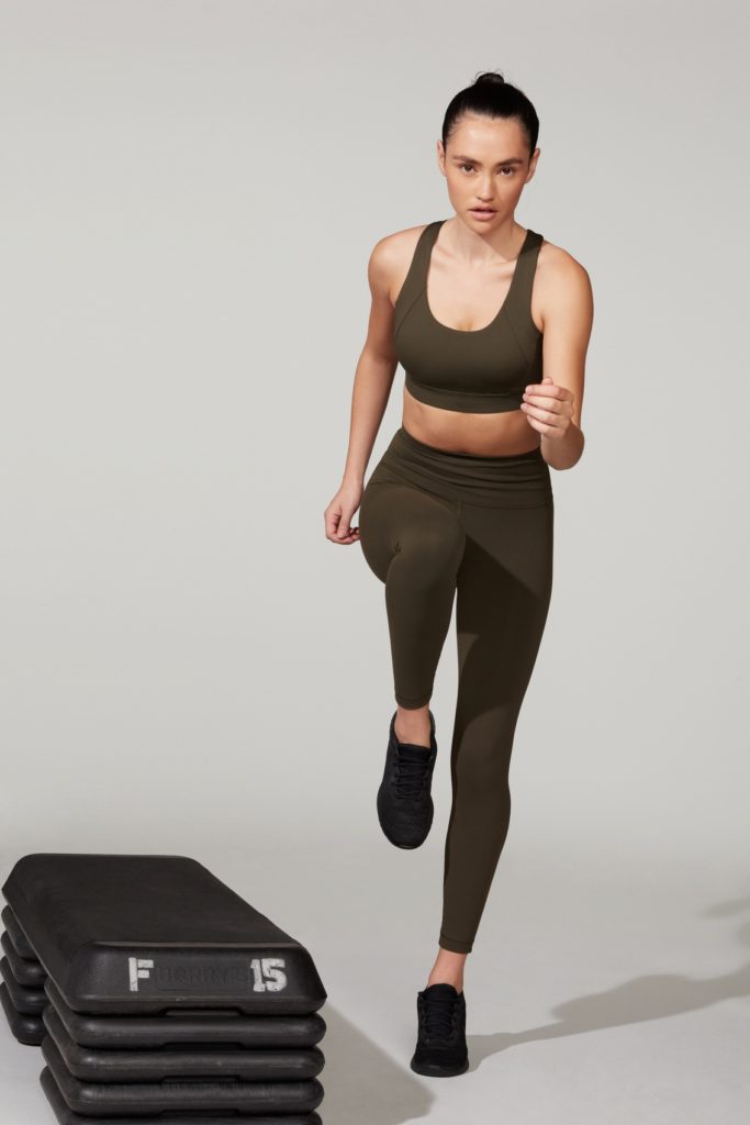 A female model with black trousers and black top in gym