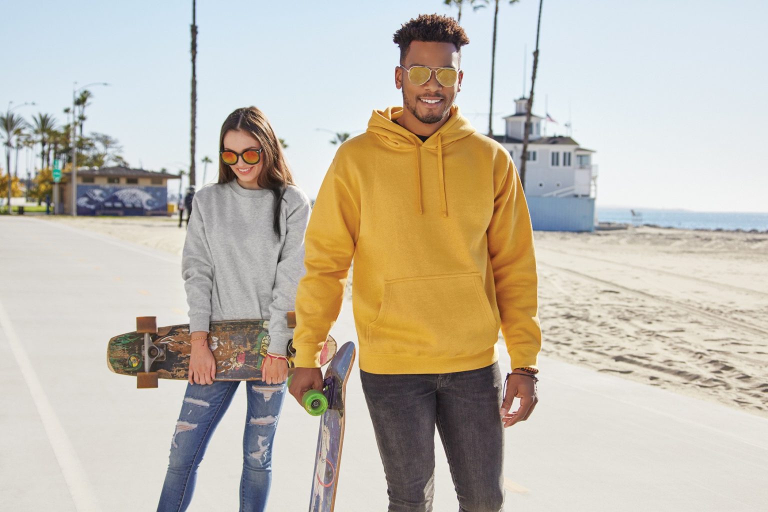 A male and female models with skate boards on road with tshirts and jeans