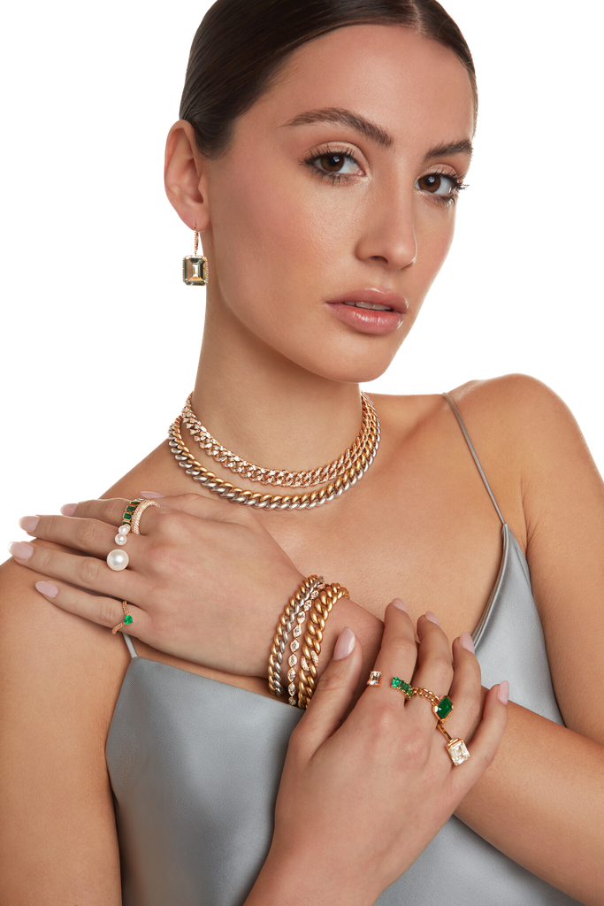 A female model holding her shoulder with her hand showing rings , bracelets and necklaces