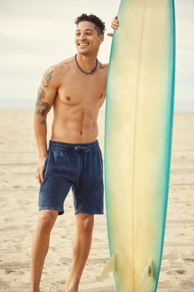 A male model with only shorts and beach skiing board