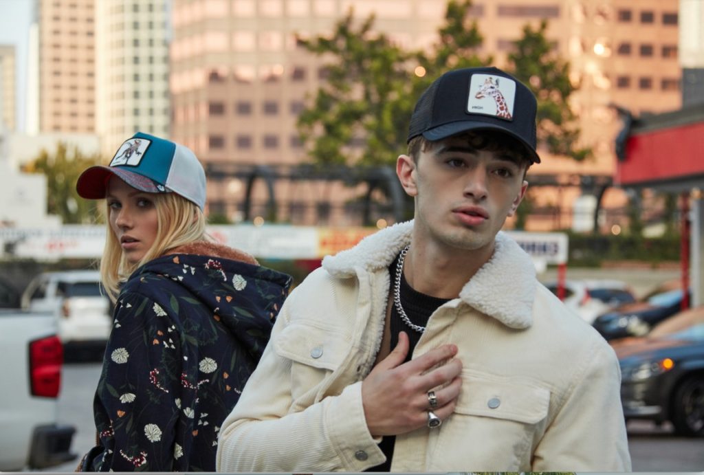 A young male model and a female model with sweaters and caps