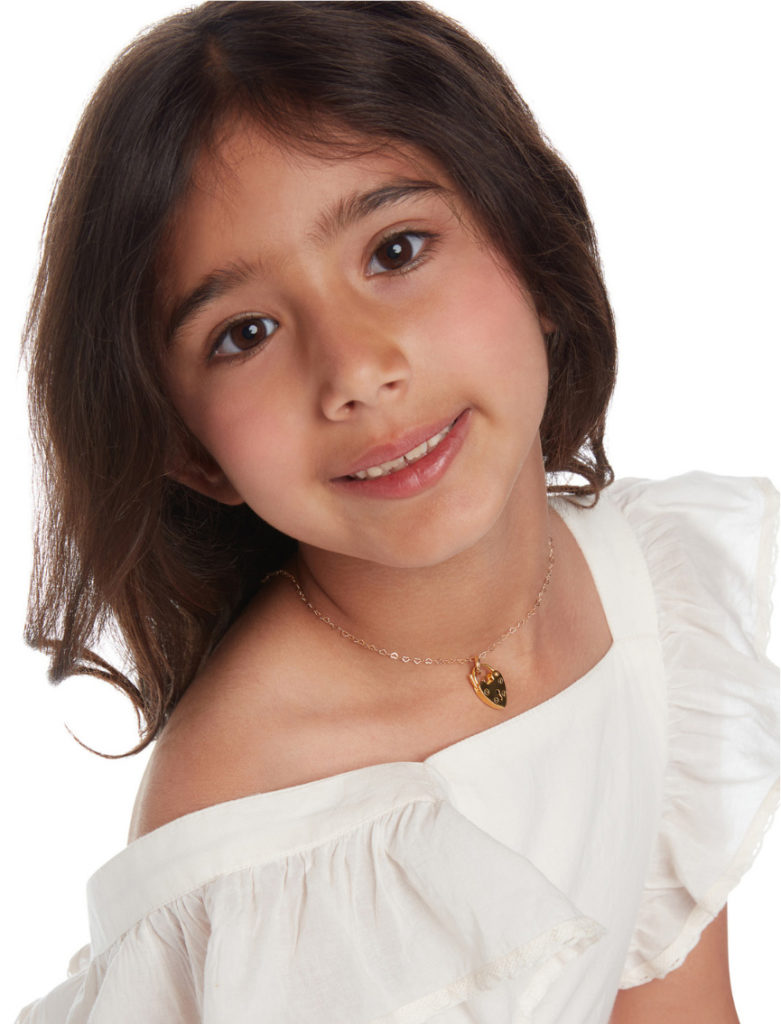 A cute little girl in white dress wearing a necklace